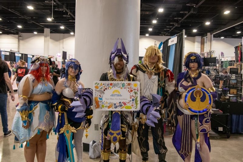 Cosplayers holding a giant library card at WasabiCon 2023